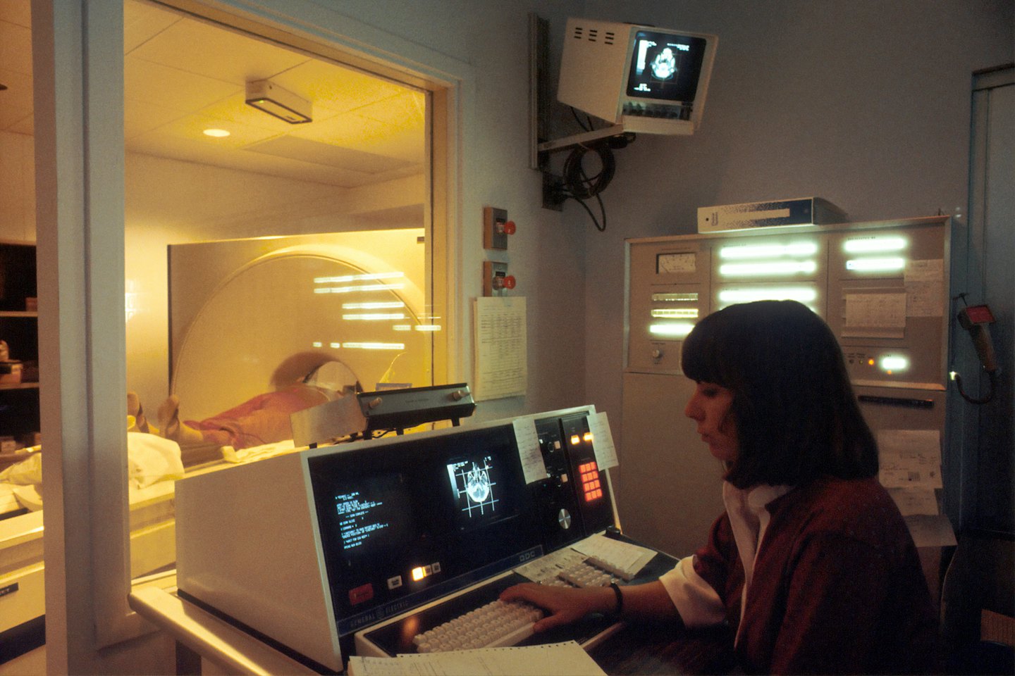 Técnico monitoriza escaneo de paciente en consola de equipo de imagen.